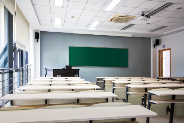 istock Empty classroom with chairs, desks and chalkboard. 1015308322