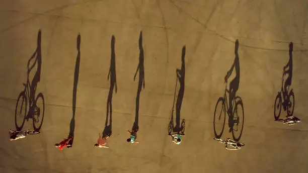 Photo of Team of Children Cast Long Shadows. Cycling, Roller Skating and Scootering