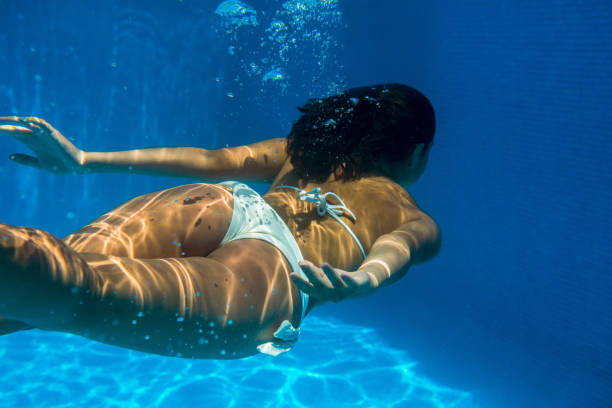 Split shot of the young woman swimming in the pool surrounded by tropical trees