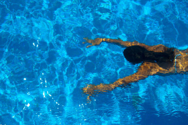 Top view of a girl swimming in a swimming pool. She is wearing a bikini and her skin is tanned.