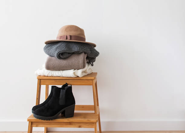 istock Stack of knitted sweaters, hat and boots near the white wall. 1015335994