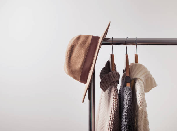 Knitted sweaters on hangers and felt hat