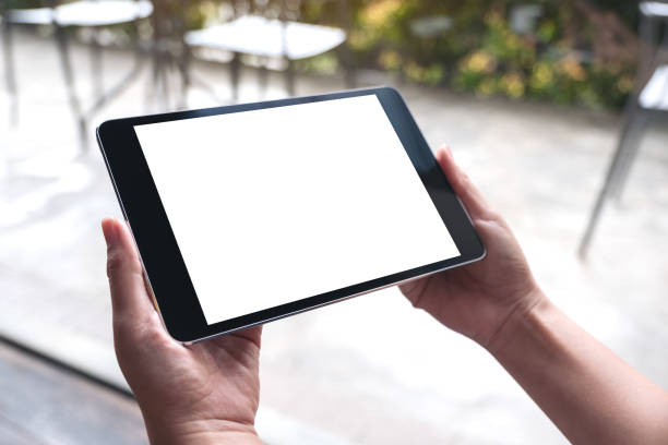 istock Mockup image of woman's hands holding black tablet pc with white blank desktop screen in cafe 1015345304