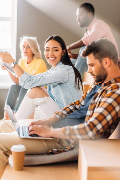 istock side view of handsome student using laptop while sitting on tribunes with classmates 1015350630