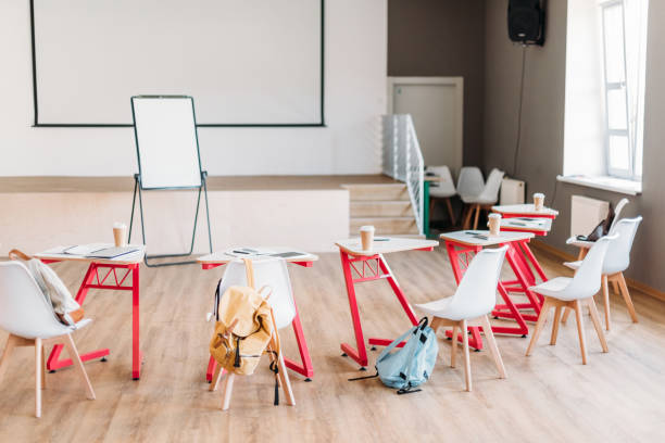 istock empty college classroom with desks and backpacks of students 1015350660