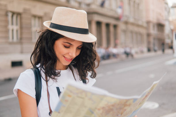 istock Young woman wearing summer hat looking at touristic map 1015352830
