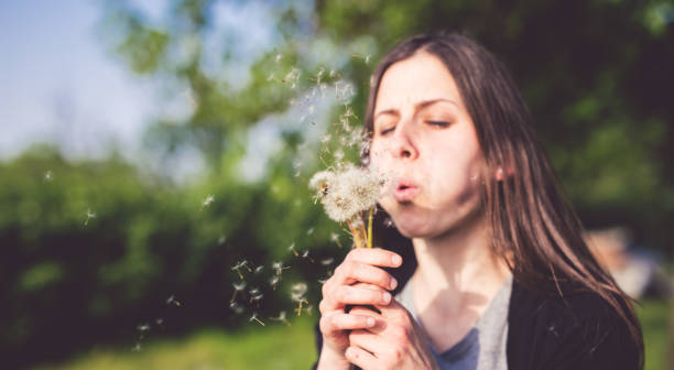 istock Young woman blows dandelion 1015357778