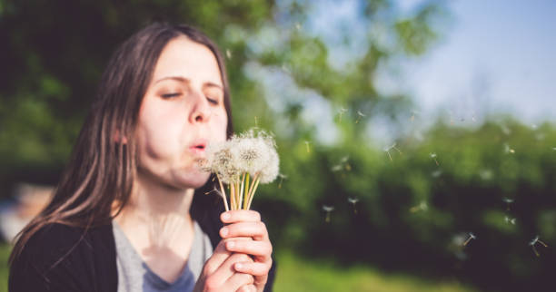 istock Young woman blows dandelion 1015357822
