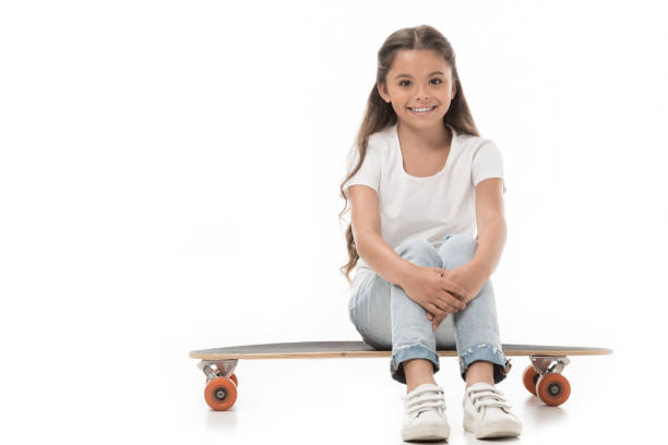 istock cheerful kid sitting on skateboard isolated on white 1015362998