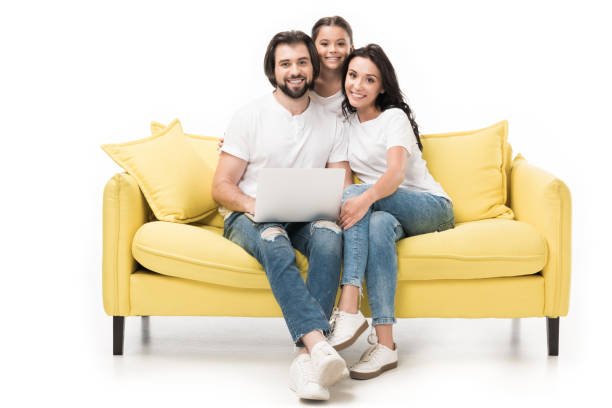 uśmiechnięta rodzina z laptopem siedzącym na żółtej kanapie odizolowanej na białym - family sofa men sitting zdjęcia i obrazy z banku zdjęć