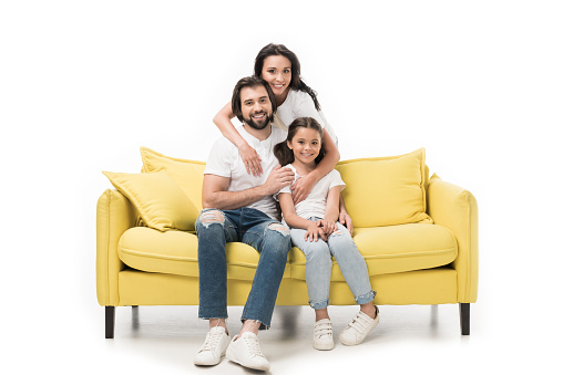 smiling woman hugging family on yellow sofa isolated on white