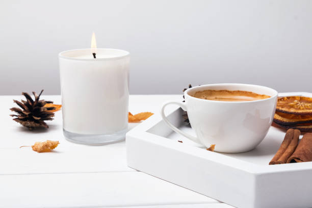 Cup, cinnamin, dry oranges and leaves and burning candle close-up