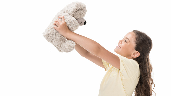 side view of cute smiling kid with teddy bear isolated on white