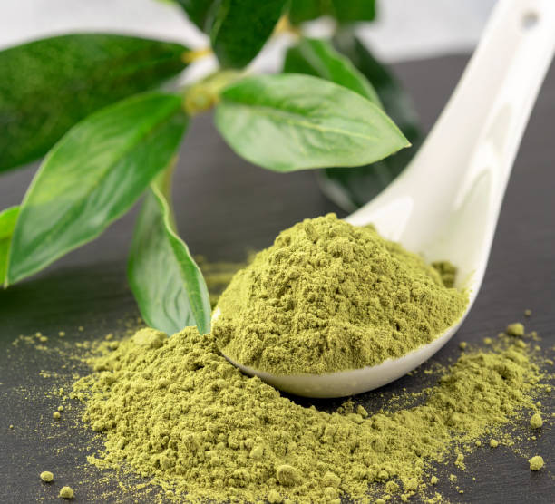 istock Matcha powder in White ceramic spoon and tea leaves on black background 1015378428
