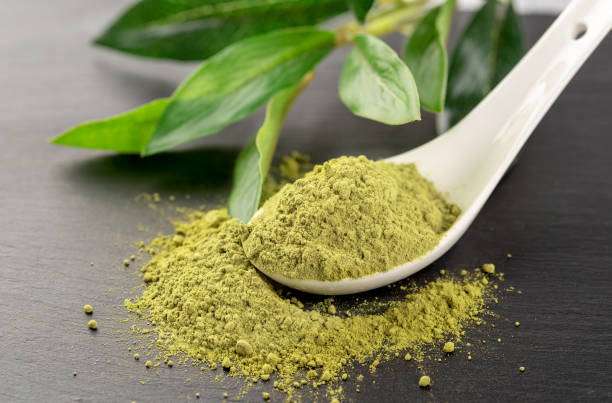 istock Matcha powder in White ceramic spoon and tea leaves on black background 1015378686