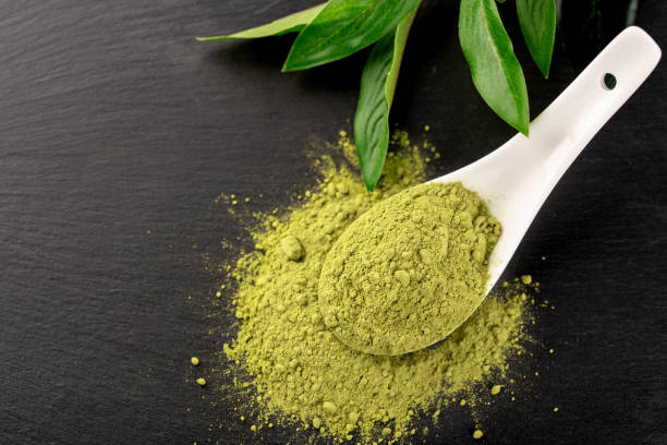 istock Matcha powder in White ceramic spoon and tea leaves on black background 1015378714