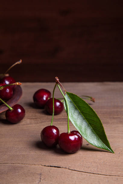 istock Clay plate with red sweet cherry on wooden background 1015378828