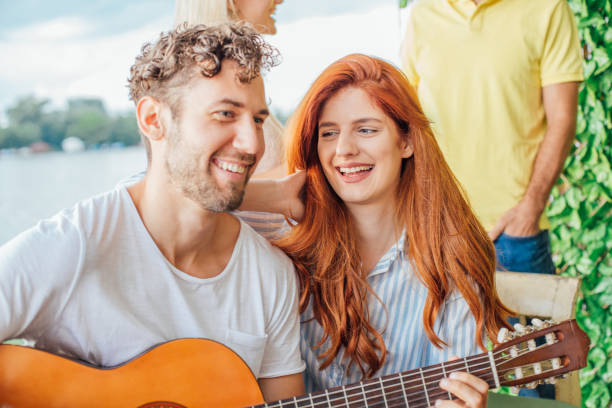 istock Beautiful redhead woman looking at guy playing guitar 1015387234