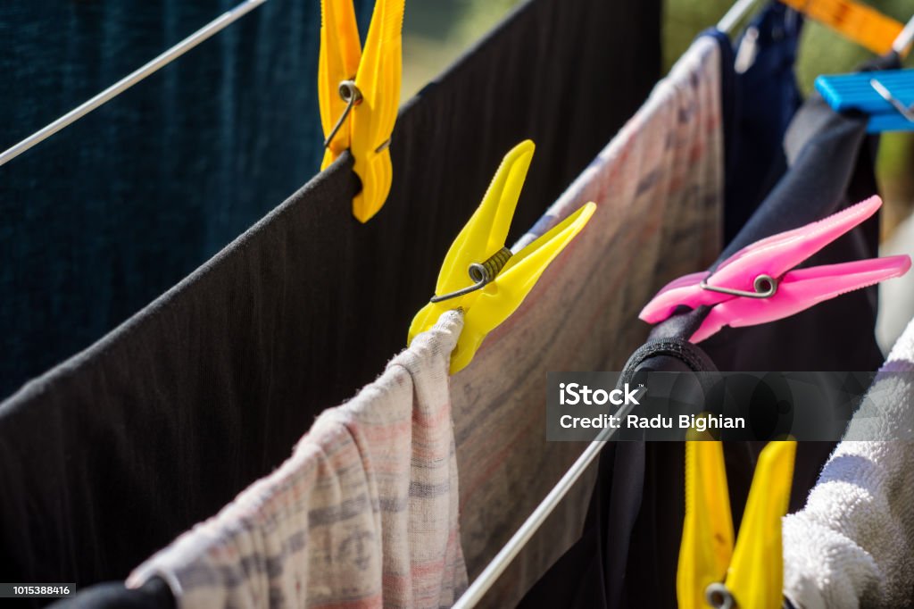 Closeup Of Plastic Clothespins Holding Clothes On Wire For Drying