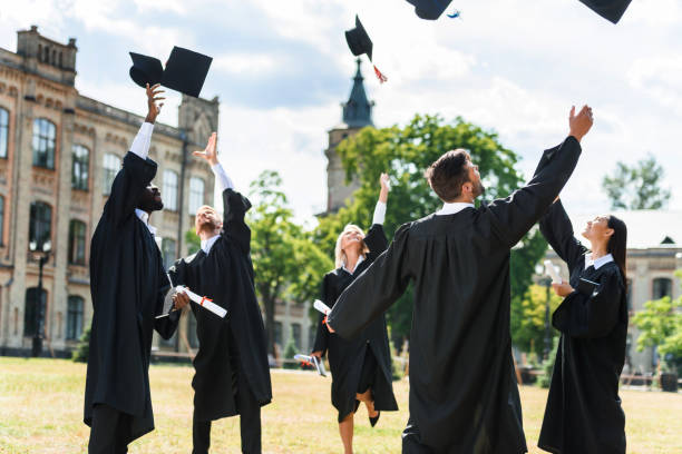 istock young graduated students throwing up graduation caps in university garden 1015394036
