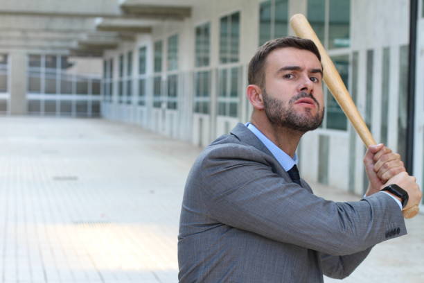 maschio dall'aspetto violento che tiene la mazza da baseball - bat weapon baseball mob foto e immagini stock