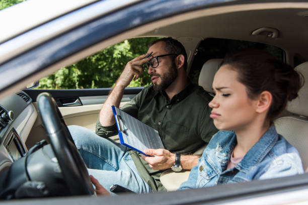 istock dissatisfied teacher touching forehead in car during driving test 1015409562