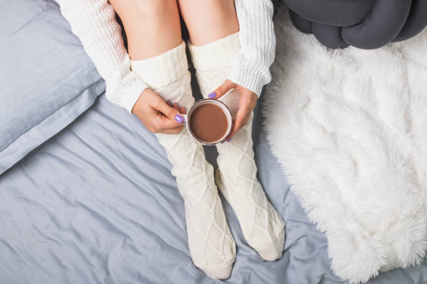 istock Woman's legs in socks and hands holding cocoa or coffee. 1015410382