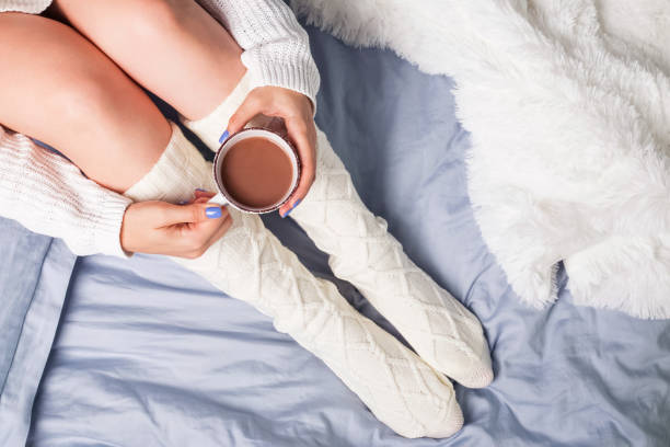 istock Woman's legs in socks and hands holding cocoa or coffee. 1015410386