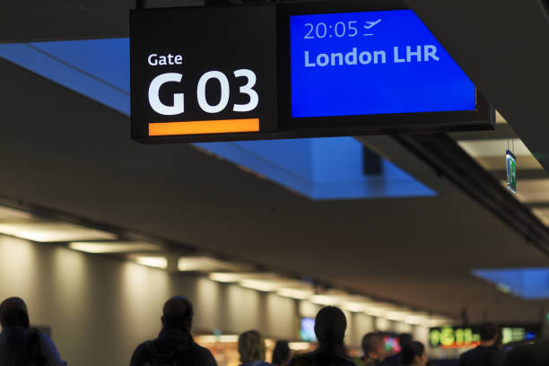 Airport interior with passenger silhouettes, gate number three board and destination 'London Heathrow Airport' (LHR) People walking in airport corridor with sign board on top heathrow airport stock pictures, royalty-free photos & images