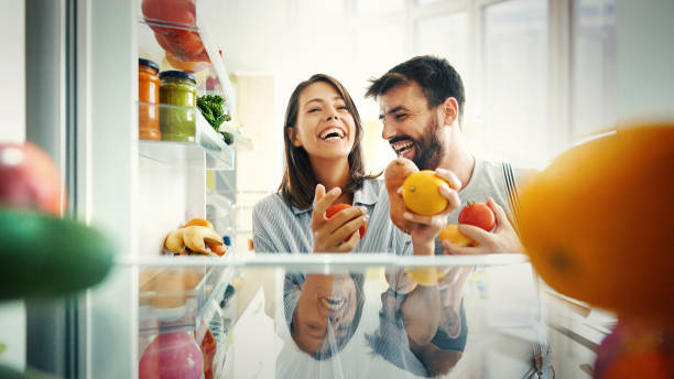 Let's have some breakfast. Closeup of a cheerful young couple picking some fruit and veggies from the fridge to make some healthy breakfast on Sunday morning. Shot from inside the working fridge. refrigerator stock pictures, royalty-free photos & images