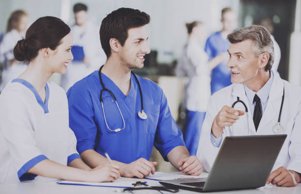 istock Group of Doctors with Laptop Discusses Operation. 1015414368