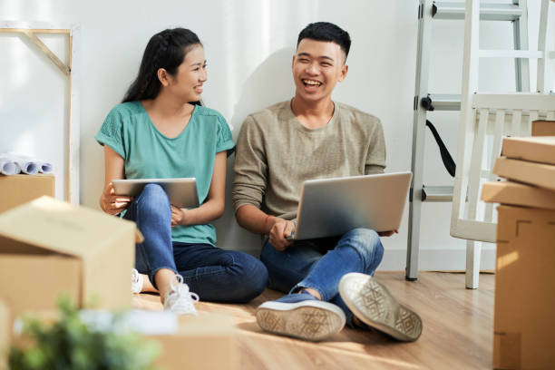 istock Laughing couple with gadgets in new apartment 1015423306