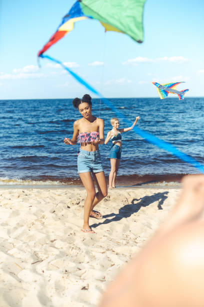 istock selective focus of multicultural friends with kites spending time on sandy beach together 1015430184