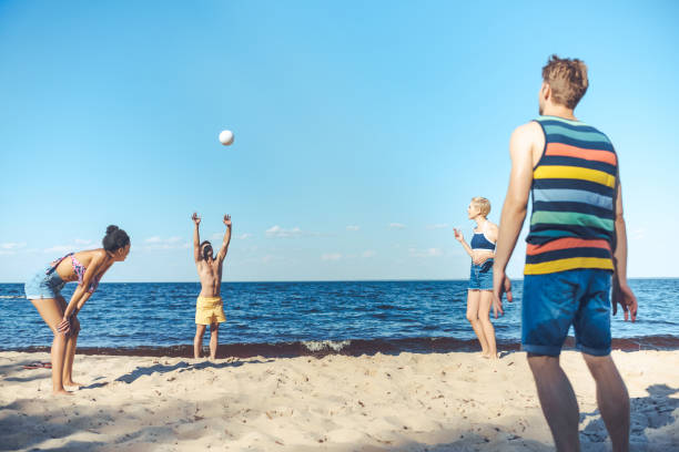 istock interracial friends playing volleyball together on sandy beach 1015430358