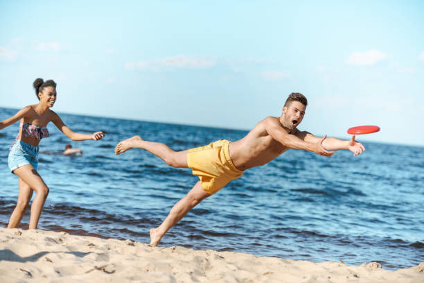 istock young multicultural couple playing with flying disc on beach on summer day 1015430532