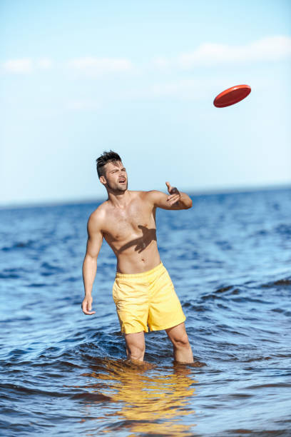 istock young man throwing flying disc while standing in sea on summer day 1015430598