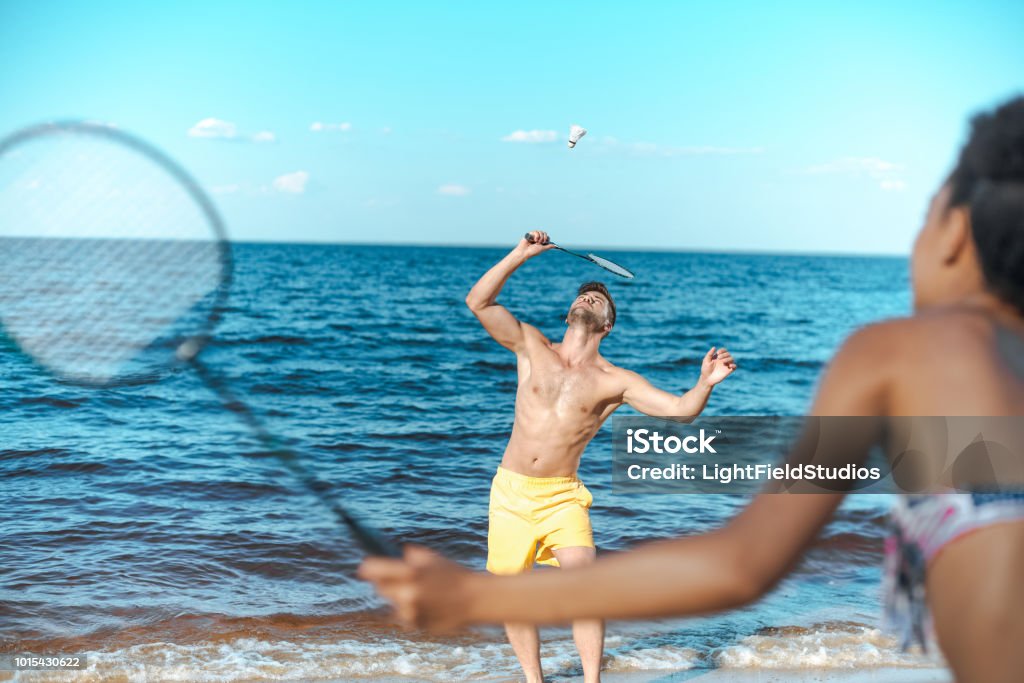 mise au point sélective de couple multiculturel, jouer au badminton sur la plage de sable fin - Photo de Adulte libre de droits