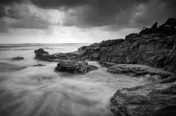istock black and white image,soft wave flow hitting the sandy beach over dark cloud background 1015434814