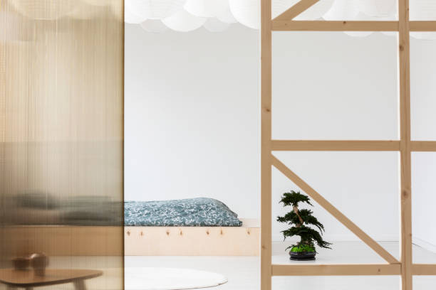 istock Bonsai next to wooden bed with patterned sheets in minimal bedroom interior with screen. Real photo 1015437084