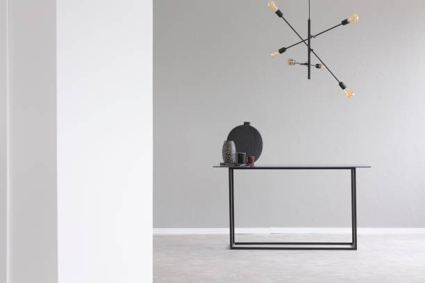 istock Lamp above black table in grey and white empty room interior with copy space. Real photo 1015437614
