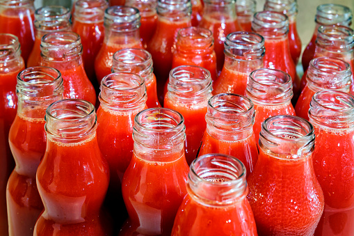 Bottles of homemade tomato juice waiting to be capped