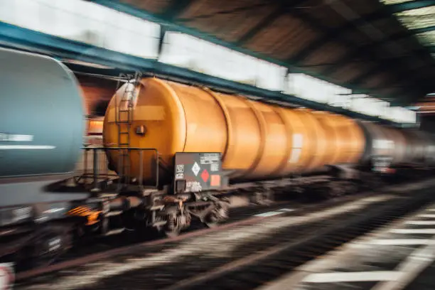 Freight train with tanks in motion crossing a railroad station