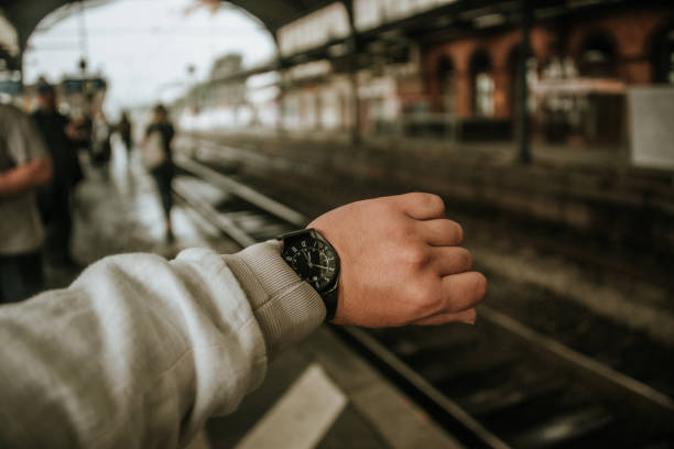 A human ahnd with a wristwatch at a railroad station