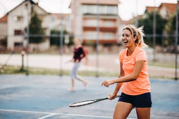 glückliche junge mädchen tennis spielen - doubles stock-fotos und bilder
