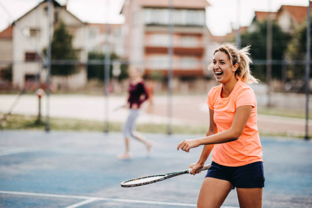 счастливые молодые девушки, играющие в теннис - doubles стоковые фото и изображения