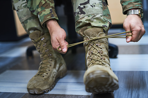 Cropped shot of a soldier tying his boot shoelaces in the dorms of a military academy