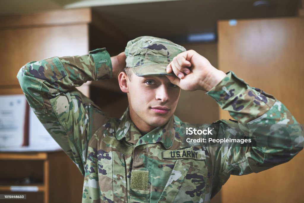 In a world where you can be anything, be brave Shot of a young soldier standing getting dressed in the dorms of a military academy Military Stock Photo