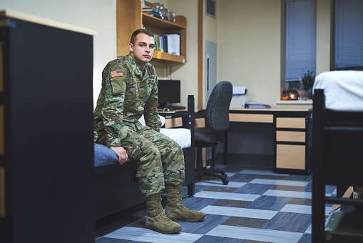 Shot of a young soldier sitting on his bed in the dorms of a military academy