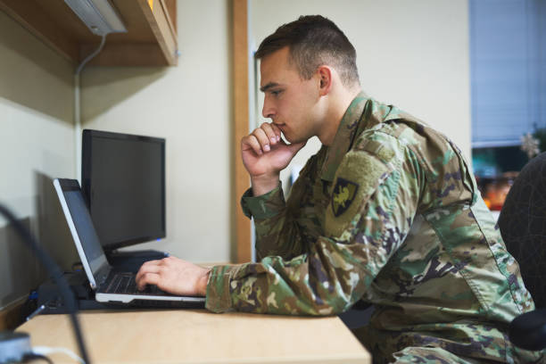 Education, the most powerful tool there is Shot of a young soldier using a laptop in the dorms of a military academy patriotic man stock pictures, royalty-free photos & images