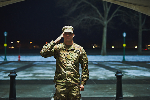 Shot of a young soldier standing at a military academy and saluting